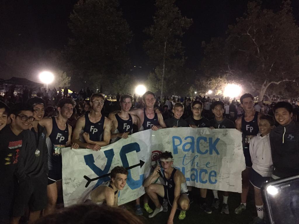 Boys' Cross Country holding the Pack the Place banner after their meet.